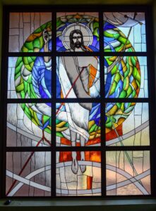 Witraż Jezus w kościelnym oknie. postać na tle koła z krzyżem